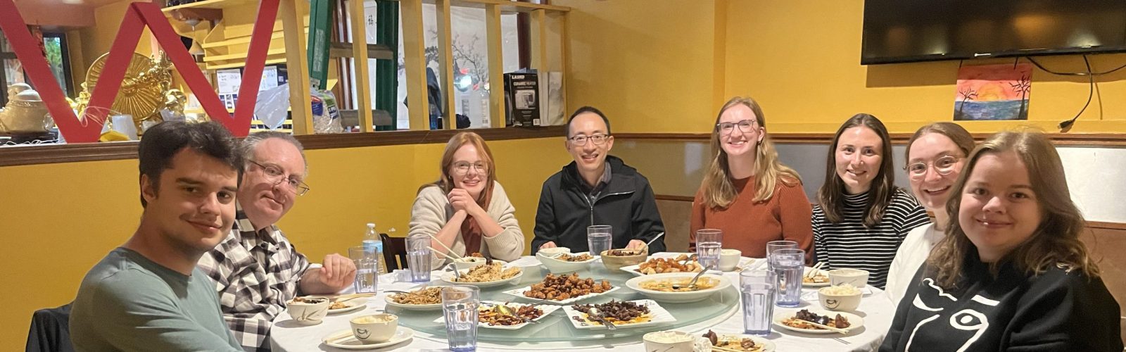 A group of 8 individuals sit around a round dinner table.